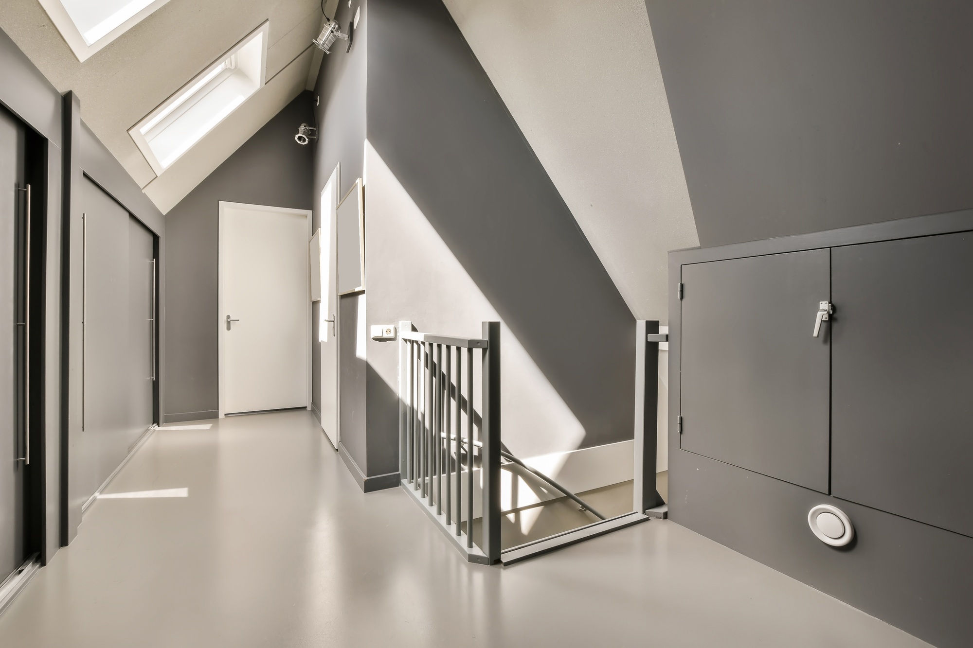 a long white hallway with stairs and a metal railing