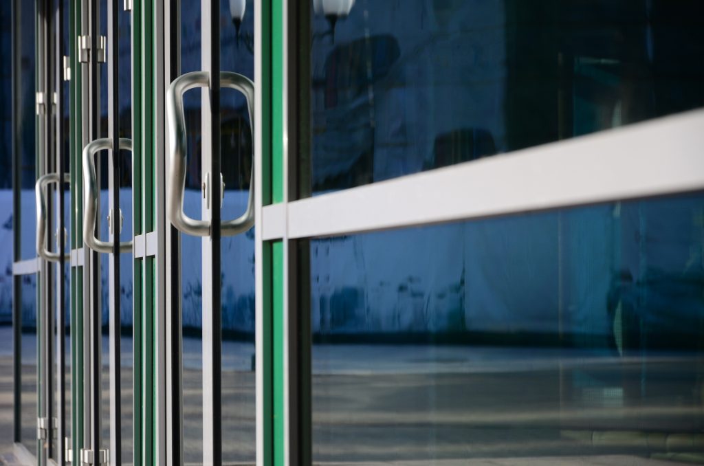 Chrome door handle and glass of modern aluminium door outside the office building