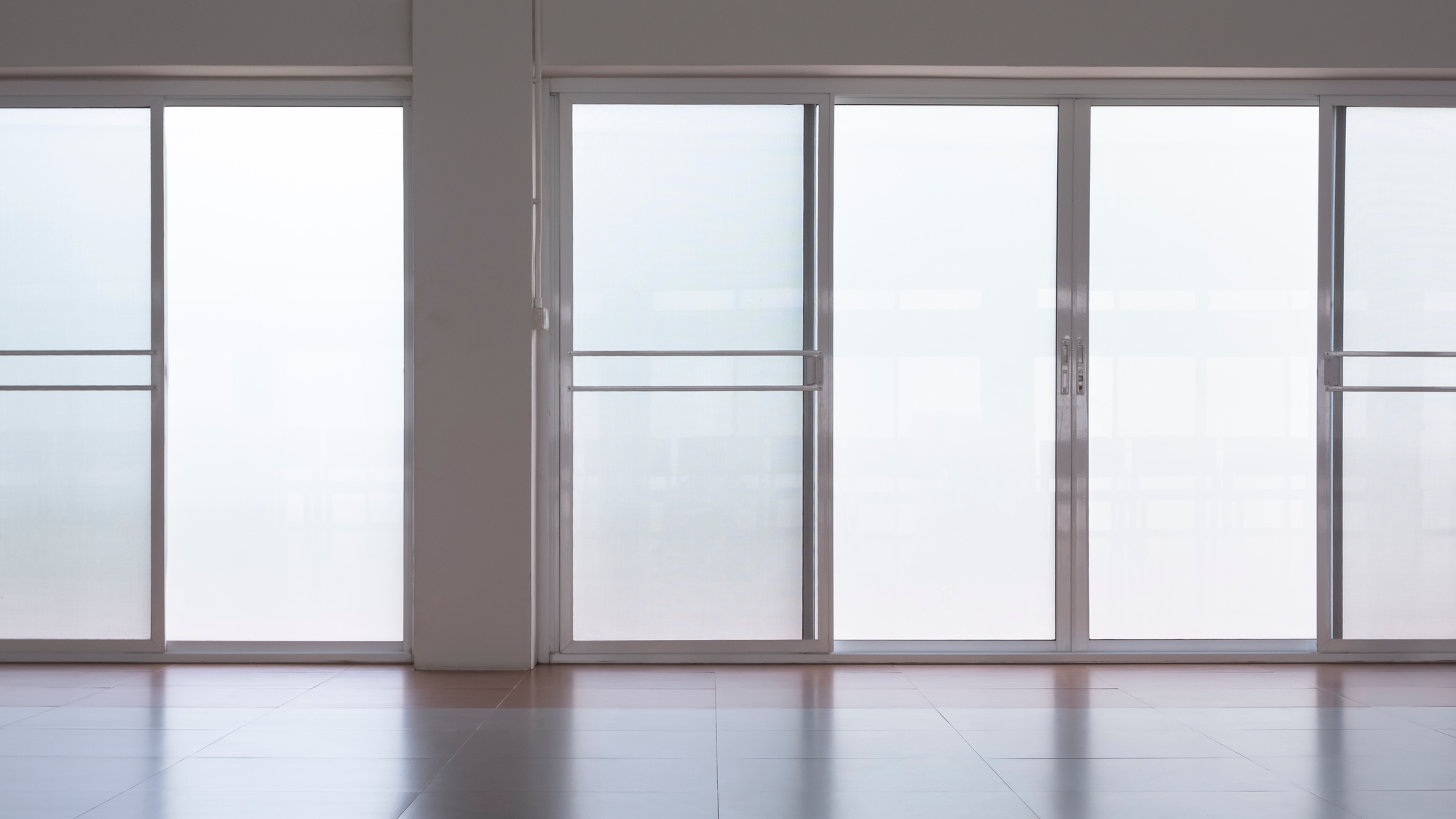 frosted glass sliding doors with screen doors and light reflection on tile floor in empty room