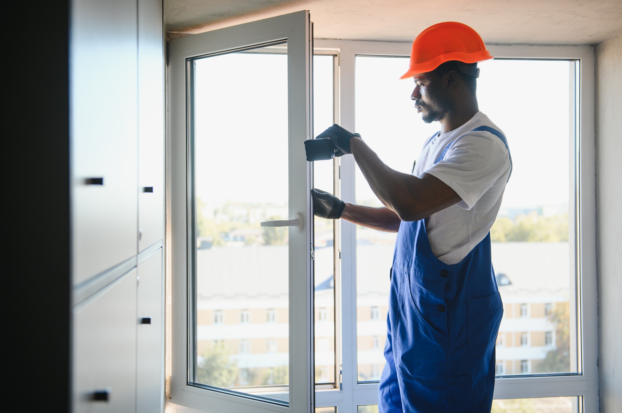 Worker in installing white plastic upvc window on house